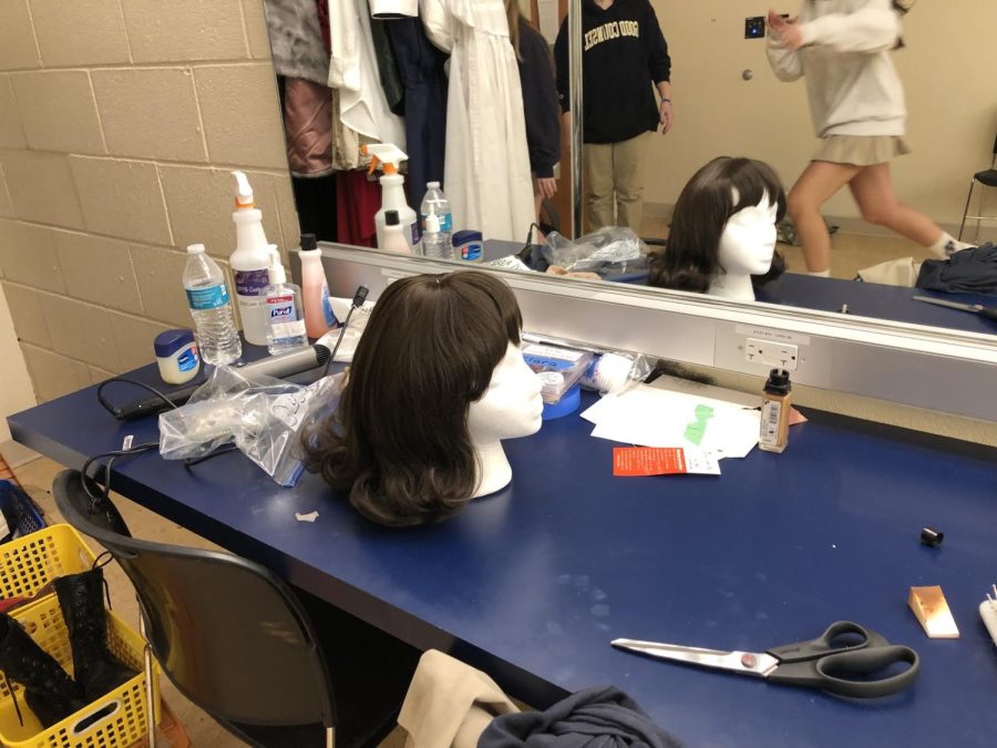 A styled wig and cosmetics backstage in the makeup/dressing room.